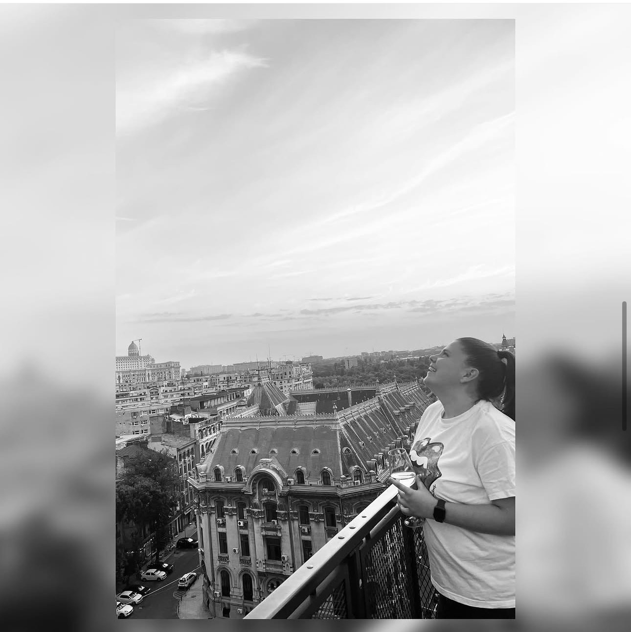 Roxi râzând pe o terasă cu vedere la oraș
