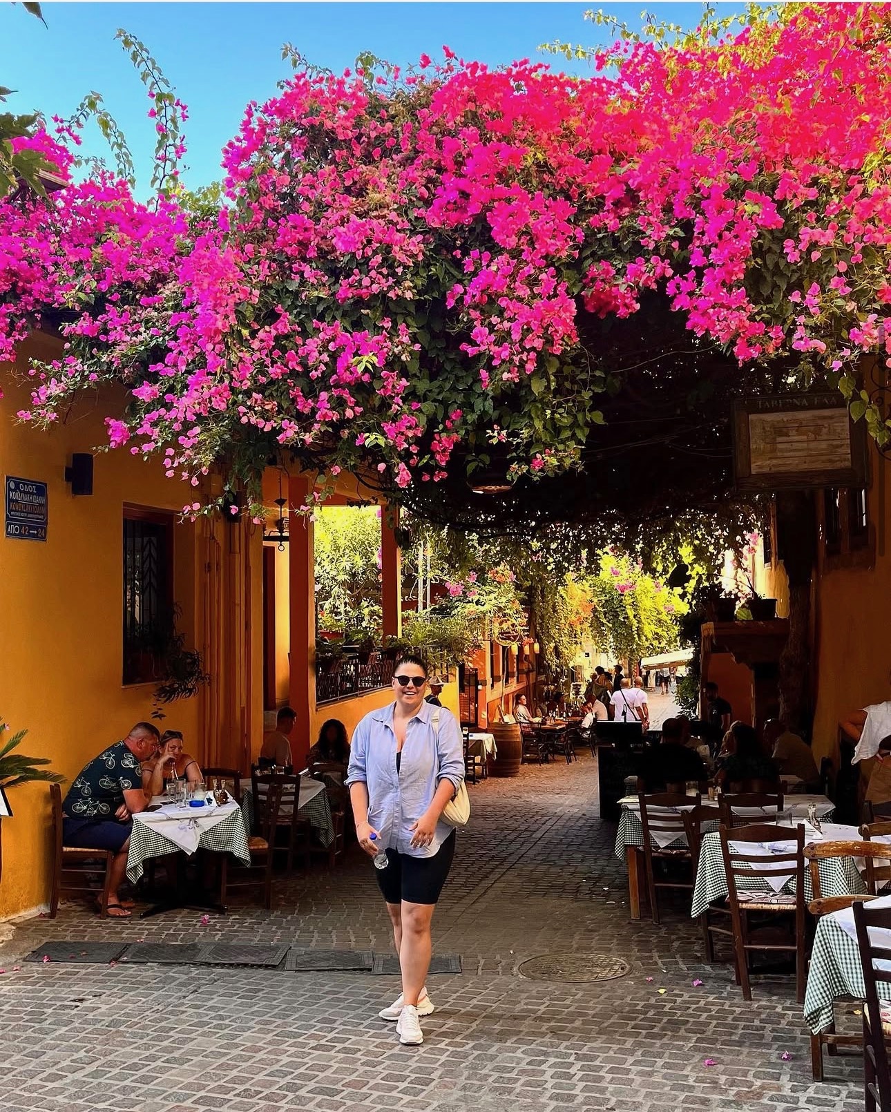 Roxi mergând pe sub flori roz de bougainvillea